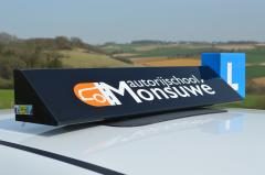 Het dakbord van Autorijschool Ruud Monsuwé op de lesauto, met het blauwe L-bordje