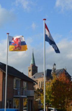 De Limburgse en Nederlandse vlag in Hulsberg, met de kerk op de achtergrond