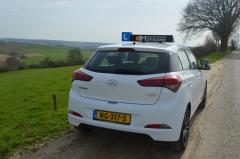 De lesauto van achteren op een landweg bij Hulsberg