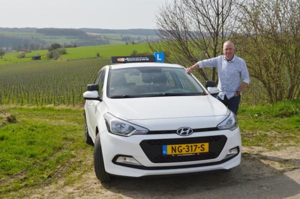 Ruud Monsuwé naast zijn lesauto in het heuvelland bij Hulsberg